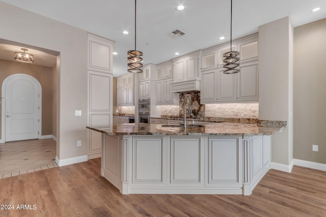 kitchen featuring dark stone countertops, pendant lighting, decorative backsplash, and kitchen peninsula