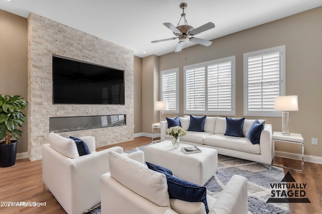 living room with wood-type flooring, ceiling fan, and a fireplace