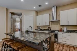 7409 E Weaver Way, Prescott Valley, AZ 86314 - kitchen with wall chimney exhaust hood, stainless steel range, a kitchen breakfast bar, white cabinets, and recessed lighting