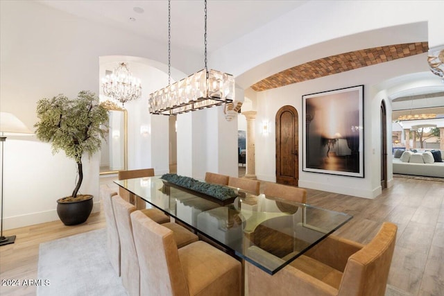 dining space featuring ornate columns, lofted ceiling, and light hardwood / wood-style flooring