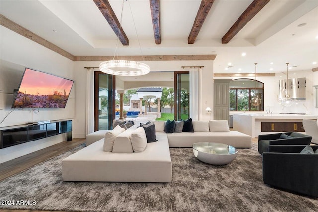 living room featuring dark wood-type flooring, beamed ceiling, and an inviting chandelier