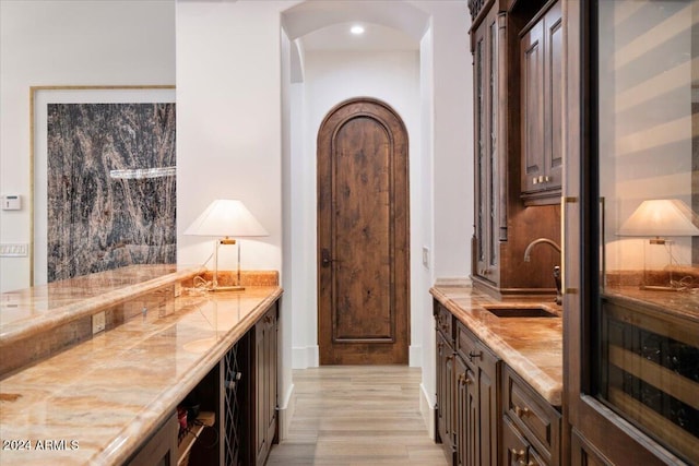 interior space with light hardwood / wood-style floors, dark brown cabinetry, and sink