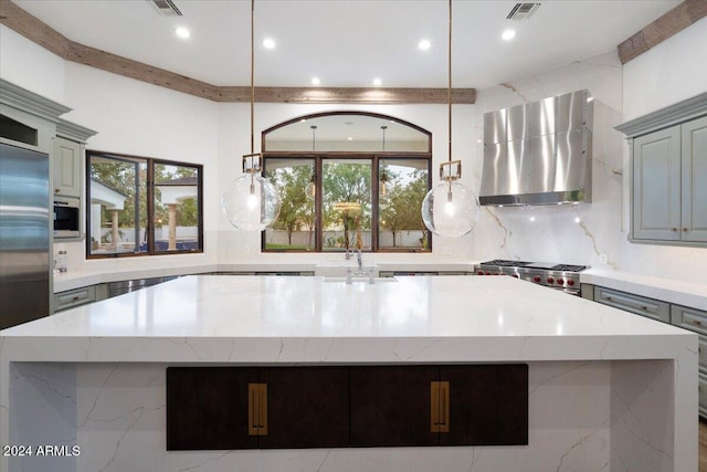 kitchen with an island with sink, hanging light fixtures, stainless steel appliances, and extractor fan