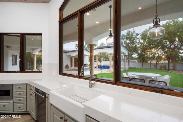 kitchen with gray cabinetry, wood-type flooring, vaulted ceiling, light stone countertops, and appliances with stainless steel finishes