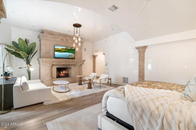 living room featuring a large fireplace, decorative columns, and light wood-type flooring