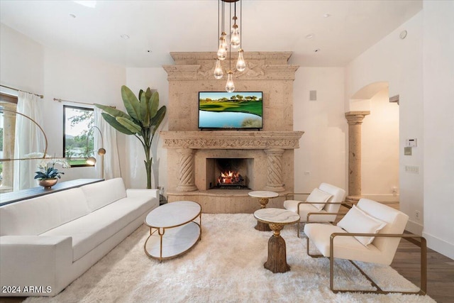 living room featuring light hardwood / wood-style flooring, a high end fireplace, and decorative columns