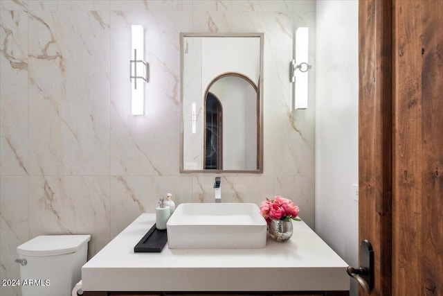 bathroom with vanity, toilet, and tile walls