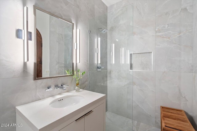 bathroom with vanity, decorative backsplash, a tile shower, and tile walls