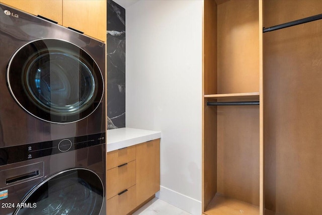 clothes washing area with stacked washer / dryer and cabinets