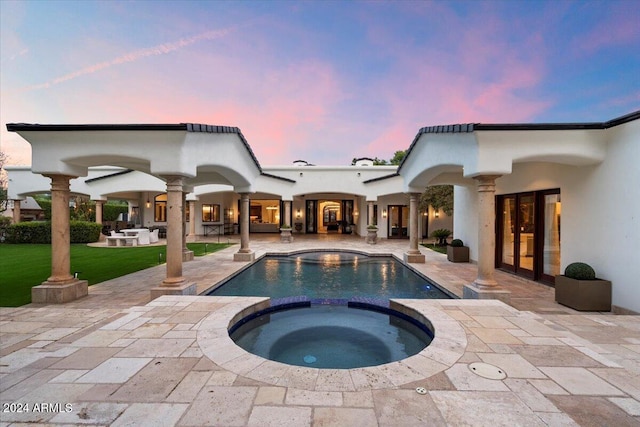 pool at dusk with a yard, a patio area, french doors, and an in ground hot tub