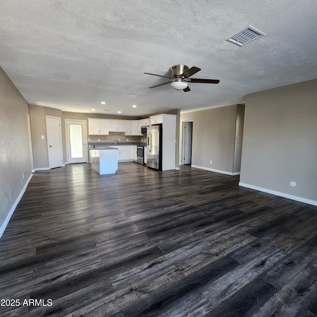 unfurnished living room featuring ceiling fan, dark hardwood / wood-style flooring, and a textured ceiling