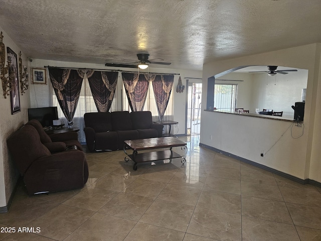 living room with ceiling fan, tile patterned floors, and a textured ceiling