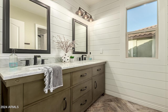 bathroom with wood walls, vanity, and parquet flooring