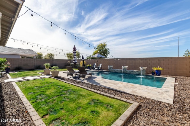 view of swimming pool featuring pool water feature, a yard, and a patio