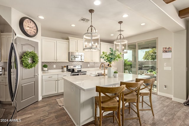 kitchen featuring pendant lighting, a center island with sink, white cabinets, sink, and stainless steel appliances