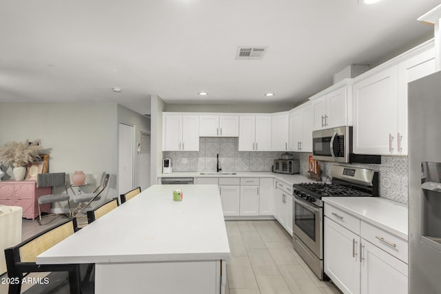 kitchen with visible vents, decorative backsplash, appliances with stainless steel finishes, light countertops, and a sink