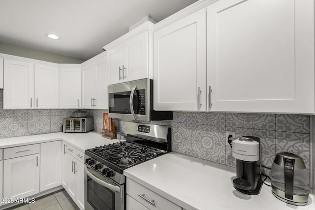 kitchen with appliances with stainless steel finishes, white cabinets, light countertops, and backsplash