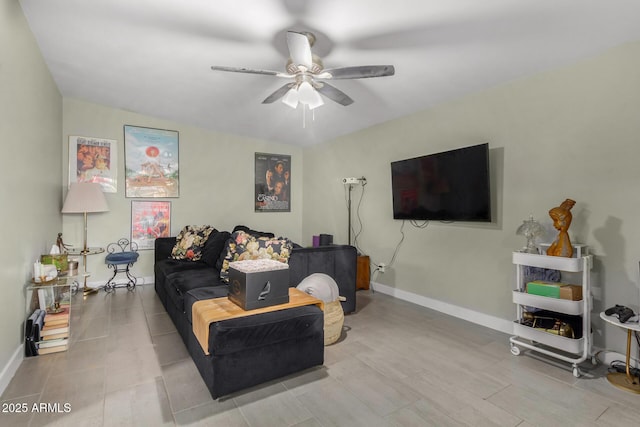 living area with a ceiling fan and baseboards