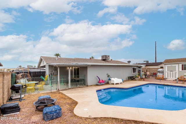 view of swimming pool with a fenced in pool, a patio, central AC unit, an outdoor fire pit, and a fenced backyard