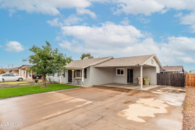 ranch-style home featuring driveway, a front lawn, a shingled roof, and fence