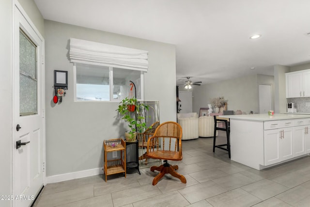 kitchen featuring tasteful backsplash, light countertops, white cabinetry, ceiling fan, and baseboards