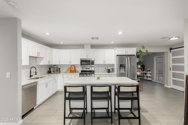 kitchen featuring stainless steel appliances, light countertops, visible vents, a barn door, and a sink