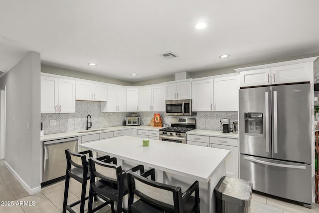 kitchen with white cabinetry, appliances with stainless steel finishes, light countertops, and a sink