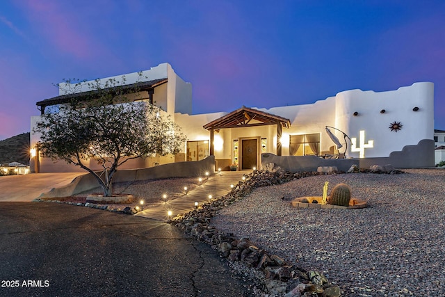pueblo-style house with driveway and stucco siding
