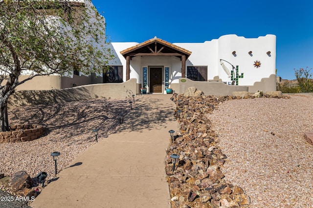 view of front facade with stucco siding and fence