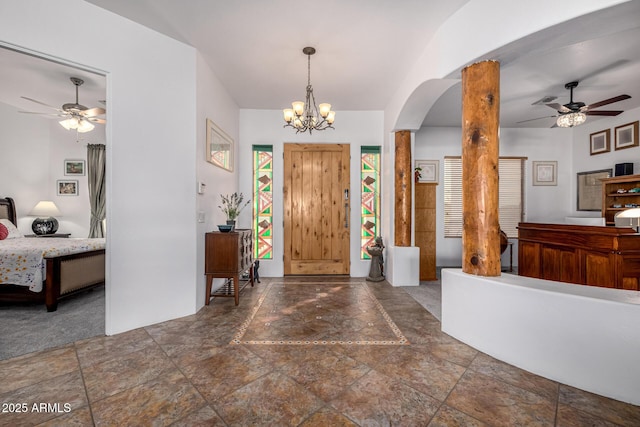 foyer entrance with arched walkways, stone tile floors, and ceiling fan with notable chandelier