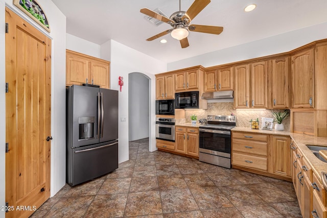 kitchen with a ceiling fan, backsplash, under cabinet range hood, appliances with stainless steel finishes, and arched walkways