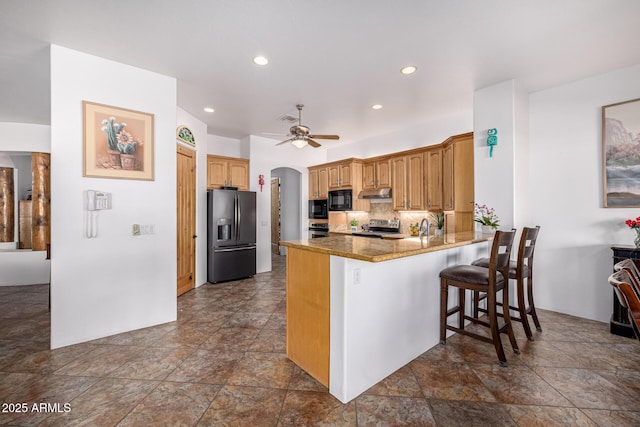 kitchen with arched walkways, ceiling fan, a peninsula, under cabinet range hood, and black appliances