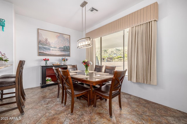 dining area with visible vents, a notable chandelier, and stone finish flooring
