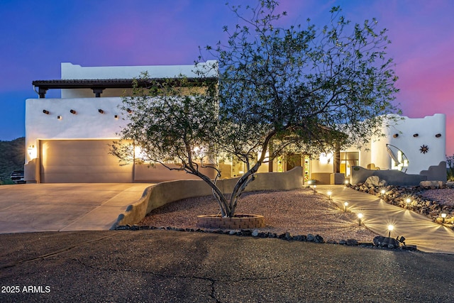 view of front of home featuring an attached garage, driveway, and stucco siding