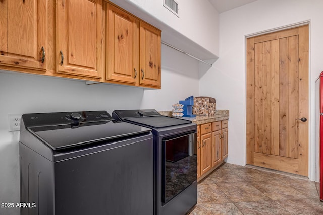 washroom featuring cabinet space, visible vents, separate washer and dryer, and stone finish flooring