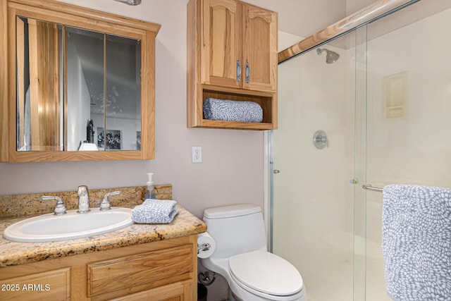 bathroom featuring toilet, a stall shower, and vanity