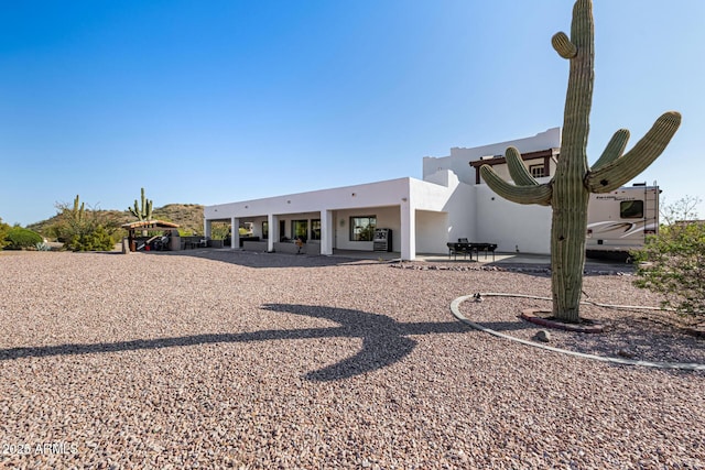 rear view of property featuring a patio and stucco siding