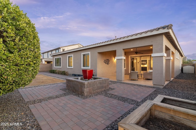 back house at dusk featuring a patio area and ceiling fan