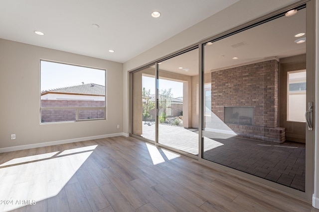 empty room featuring a brick fireplace and light hardwood / wood-style flooring