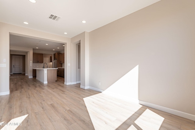 unfurnished living room featuring light hardwood / wood-style floors and sink