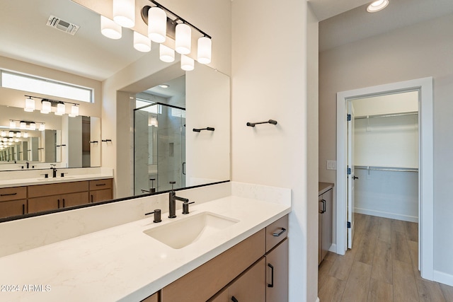 bathroom with hardwood / wood-style flooring, vanity, and walk in shower