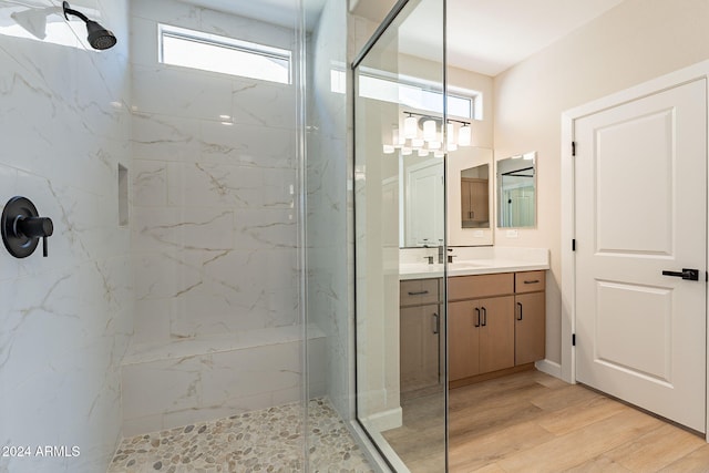 bathroom with tiled shower, hardwood / wood-style floors, and vanity