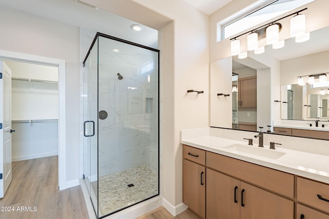 bathroom with wood-type flooring, vanity, and a shower with door