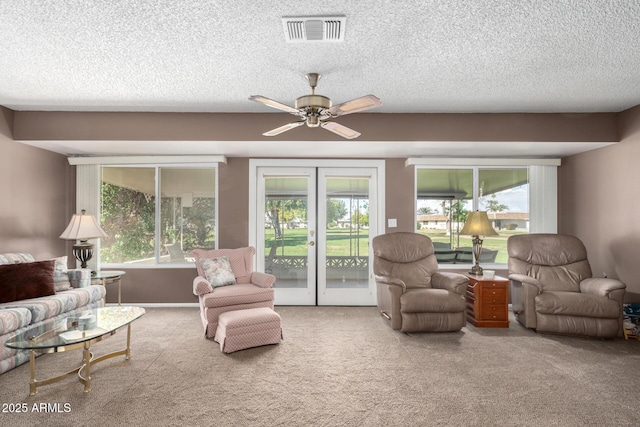 carpeted living room with a textured ceiling, ceiling fan, and french doors