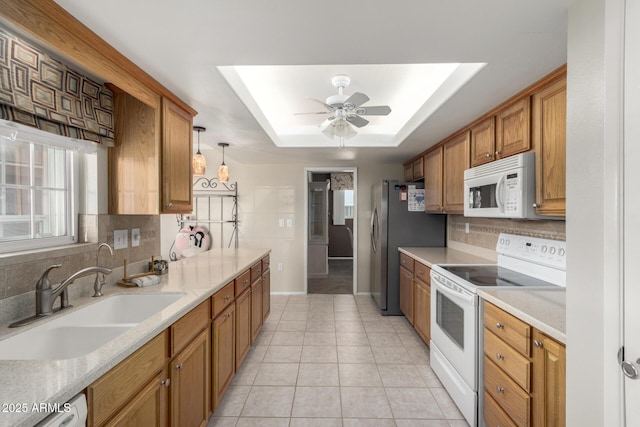 kitchen with sink, light tile patterned floors, a tray ceiling, pendant lighting, and white appliances