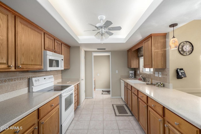 kitchen with sink, hanging light fixtures, light tile patterned floors, a tray ceiling, and white appliances