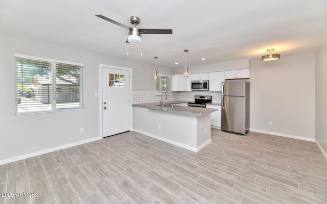 kitchen with a wealth of natural light, a peninsula, a sink, and appliances with stainless steel finishes