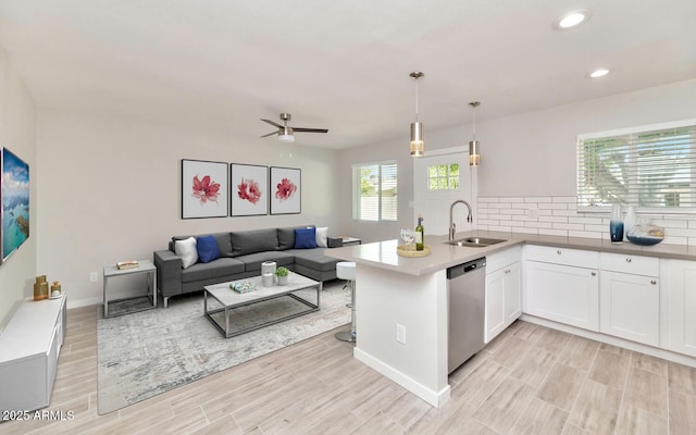 kitchen with recessed lighting, a peninsula, wood tiled floor, dishwasher, and a sink