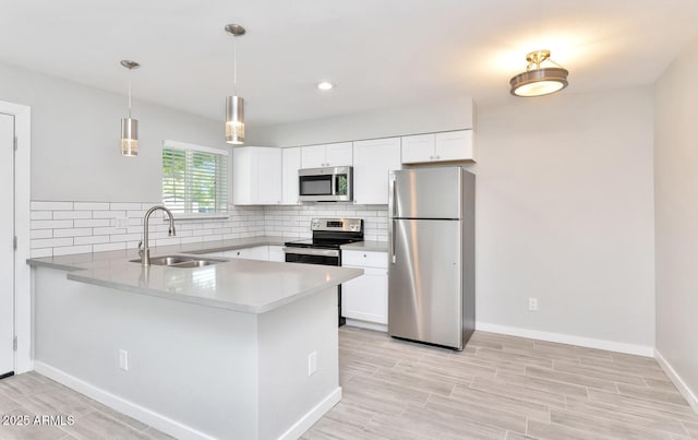 kitchen with a peninsula, white cabinets, a sink, stainless steel appliances, and decorative backsplash