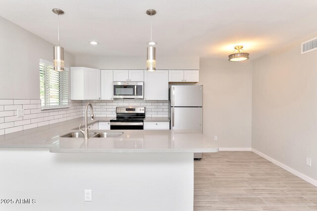 kitchen featuring stainless steel appliances, a peninsula, a sink, and tasteful backsplash